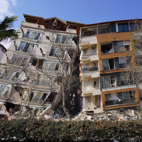 Two apartment buildings severely damaged from an earthquake with the buildings leaning into each other.