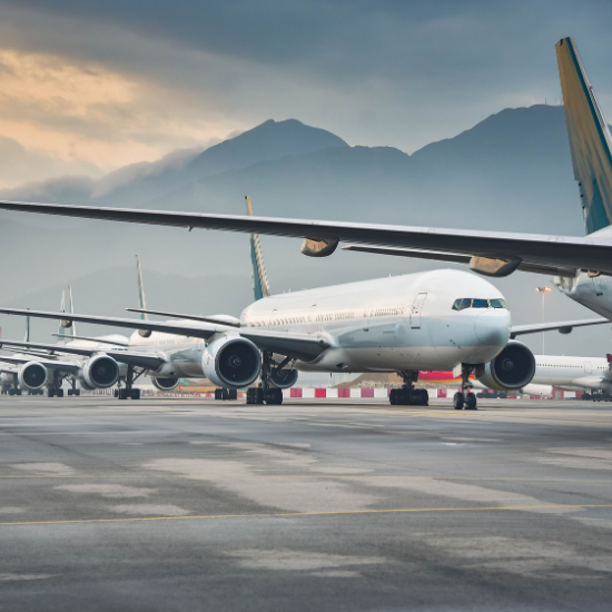 A series of jets on a flight line with mountains in the distance.