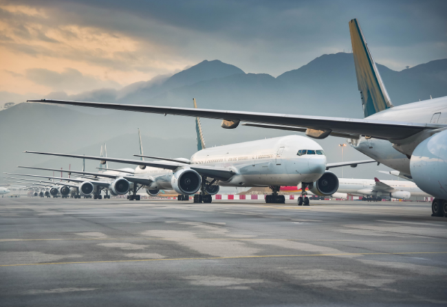 A series of jets on a flight line with mountains in the distance.