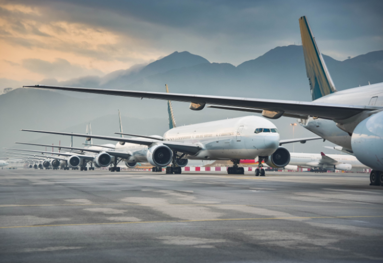 A series of jets on a flight line with mountains in the distance.