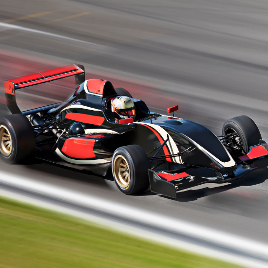 A red and black race car is in focus while the track around it is blurry, showing the care is moving very fast.